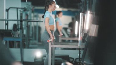 Atletik kadın modern bir spor salonunda halterle antrenman yapıyor.