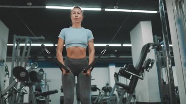 Beyaz kadın göğüs kaslarını spor salonundaki kablo çapraz makinesinde çalıştırıyor.