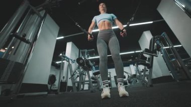 Kaslı bir vücudu olan kararlı bir sporcu, göğüs kaslarını kablo çapraz makinesinde çalıştırıyor.