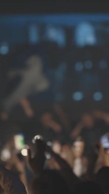 Konserde el feneri olan bir sürü insan ellerini sallıyor. Orta çekim