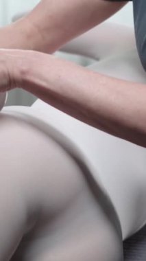 LPG masajı yaptıran bir kadın aleti kalçasından geçirir. Orta çekim