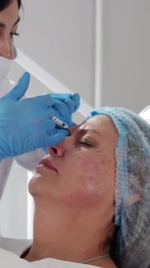 Kozmetik uzmanı olgun kadınların yüzüne yaşlanma önleyici iğne yapıyor.