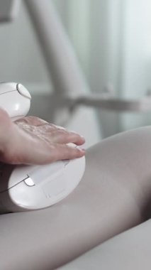 LPG masajı yaptıran bir kadın beyaz takım elbiseli genç bir kadının kalçasına masaj yapıyor. Orta çekim