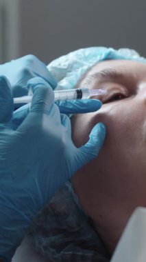 Kozmetik tedavisi. Yetişkin bir kadın için göz altı güzellik iğneleri. Orta çekim