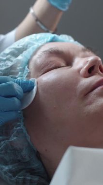 Kozmetoloji uzmanı müşterilerin elmacık kemiklerini pamukla siler. Orta çekim