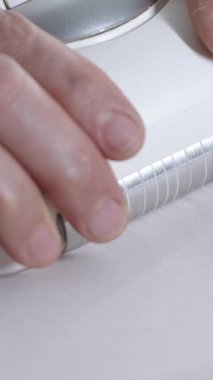 LPG masajı - terapist beyaz bez altında hastaların vücuduna karşı titreşim cihazı çalıştırıyor. Orta çekim