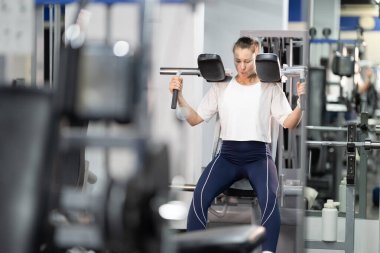 Modern bir spor merkezinde üst vücut egzersizi yapan bir kadın.