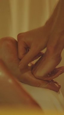 Masaj seansı. Kadın müşterisinin ayağına masaj yapan uzman terapistin elleri. Orta çekim