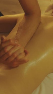 Masaj seansı. Kadın bir müşterinin yağlı sırtına masaj yapmak. Orta çekim