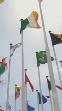 Mavi gökyüzünün arka planında rüzgarda dalgalanan farklı ülkelerin bayrakları. Orta çekim