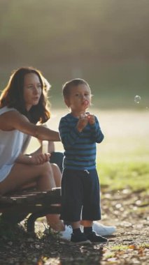 Aile parkta, sabun köpüğüyle oynayan küçük bir çocuk. Orta çekim