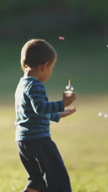 Parkta sabun köpüğüyle oynayan küçük bir çocuk. Orta çekim