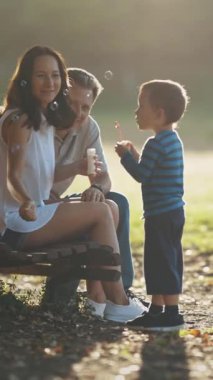 Aile parkta vakit geçiriyor. Sabun köpüğüyle oynayan tatlı bir çocuk. Orta çekim