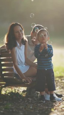 Aile parkta vakit geçiriyor. Sabun köpüğüyle oynayan küçük bir çocuk. Orta çekim