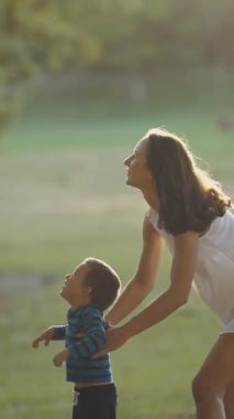 Oğlu parkta vakit geçiren sevimli, genç bir aile. Babası sabun köpüğü üflüyor. Orta çekim