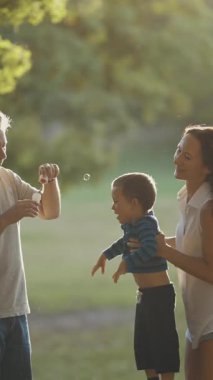 Şirin, genç bir aile parkta vakit geçiriyor. Baba sabun köpüğü üflüyor ve anne oğlunu havada büyütüyor. Orta çekim