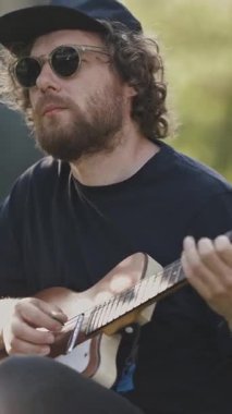 Sokakta gitar çalan genç bir adam. Orta çekim