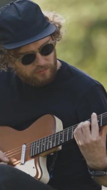 Sokakta gitar çalan genç ve şık bir adam. Orta çekim