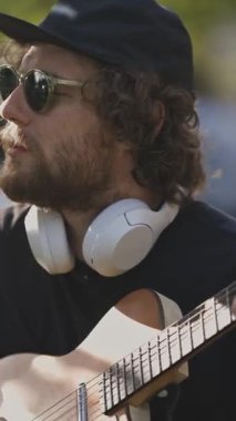 Sokakta gitar çalan gözlüklü şık bir genç adam. Orta çekim