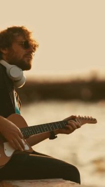 Yalnız bir genç adam şehir setinde gitar çalıyor. Orta çekim