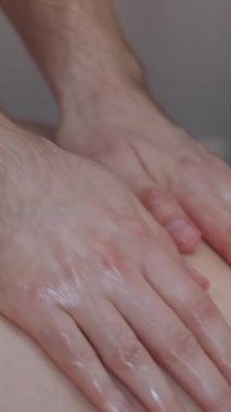 Klinikte masaj. Yağlı elleriyle bir kadının sırtına masaj yapan bir erkek terapist. Orta çekim