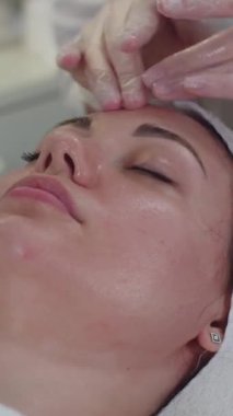 Bir kozmetologla seans. Terapist ameliyattan sonra kadın müşterinin yüzünü siliyor. Orta çekim