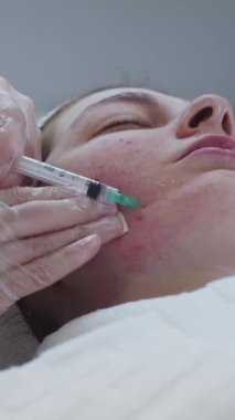 Kozmetik uzmanının randevusunda derisi sorunlu bir kadın yanağına enjeksiyon yapar. Orta çekim