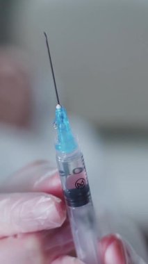 Usta kozmetik uzmanı şırıngadan fazla hava alıyor ve kanepeye müşterisine yaklaşıyor. Orta çekim