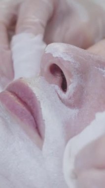 Güzellik uzmanı uygulamalı beyaz kil maskeden müşterilerin derisini siler. Orta çekim