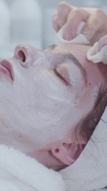 Güzellik uzmanı müşterilerin derilerini beyaz maskeden siler. Orta çekim