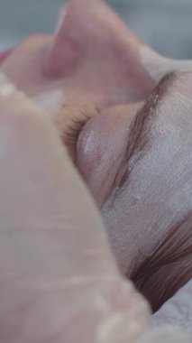 Usta, bir fırça kullanarak müşterisinin yüzüne maske takıyor. Orta çekim