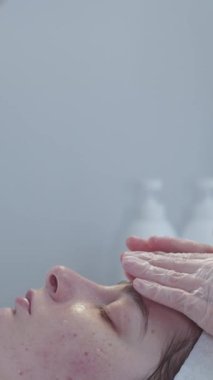 Kozmetik tedavisi. Kadın üstat ameliyattan sonra müşterisinin yüzüne yumuşak bir masaj yapıyor. Orta çekim