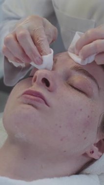 Kozmetik tedavisinde usta, pamuk pedlerle maskenin kalıntılarını müşterinin yüzünden siler. Orta çekim