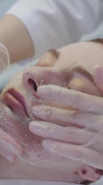 Kozmetik tedavi uzmanı kadın müşterinin yüzündeki maskenin kalıntılarını çıkarıyor. Orta çekim