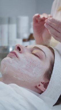 Kozmetik tedavisi, kadın müşterinin yüzündeki maskenin kalıntılarını çıkarmak. Orta çekim