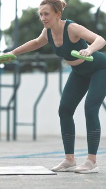 Spor sahasında ağırlık kaldıran yetişkin bir atletik kadın. Orta çekim