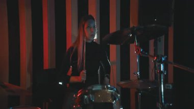Sahne ışıkları olan bir kulüpte canlı müzik gösterisi sırasında davul çalan profesyonel bayan müzisyen.