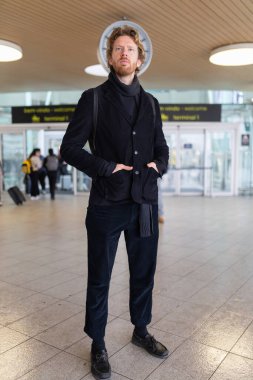 Havaalanı terminalinde beklerken el ele tutuşan genç bir yolcu.