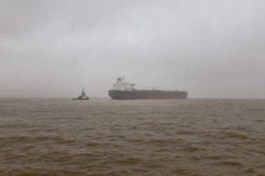 9 Şubat 2026, Lizbon, Portekiz - Sisli koşullarda büyük bir petrol tankeri gemisine rehberlik eden römorkör