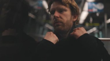 Düşünceli ve yalnız bir genç adam camında yansımasıyla toplu taşıma aracında gidip geliyor.