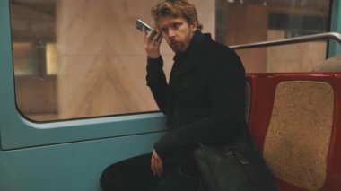 Stresli bir telefon görüşmesini dinlerken toplu taşıma araçlarında seyahat eden endişeli genç bir profesyonel.