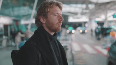 Havaalanı ya da tren istasyonunun önünde araba ya da otobüs bekleyen yakışıklı bir delikanlı.