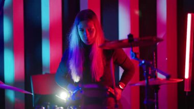 Yetenekli bir kadın, neon ışıkları olan bir gece kulübünde tek başına davul çalıyor.