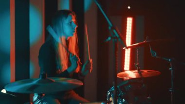 Genç bayan davulcu canlı konser ya da prova sırasında davul setinde bir rock şarkısı çalıyor.