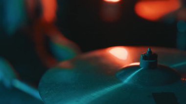 Canlı müzik performansı sırasında davul setiyle zil çalan bir davulcunun yakın çekimi.