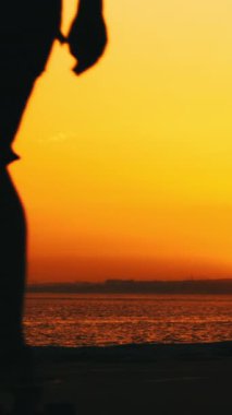 Gün batımında kaykay yapan bir adamın silüeti. Orta çekim