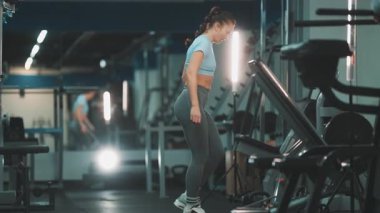 Odaklanmış atletik kadın göğüs kaslarını çalıştırmak için bir spor salonunda paralellere şınav çekiyor.