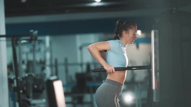 Atletik kadın destekli dalış makinesi kullanarak trisepslerini ve göğüs kaslarını güçlendiriyor.