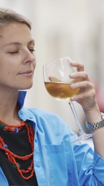 Aksesuarlı yetişkin bir kadın dışarıda beyaz şarap içiyor. Portre