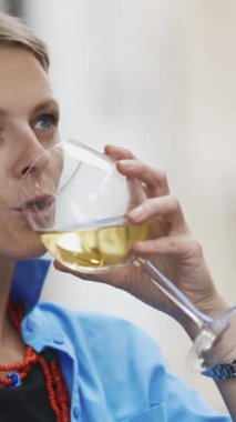 Bir kadeh şarapla yetişkin stil sahibi bir kadın video görüşmesi yapan biriyle konuşuyor. Portre